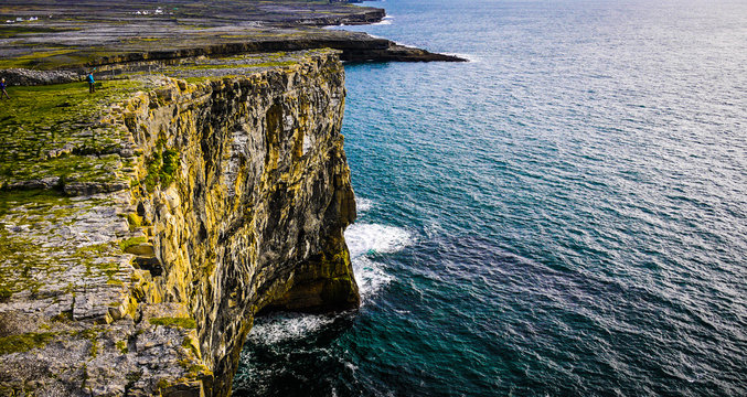 Beautiful view of the Inis M&oacute;r cliffs on a cloudy day. Taken from the top of the high cliff edge, showing the fields and ocean on a calm day.