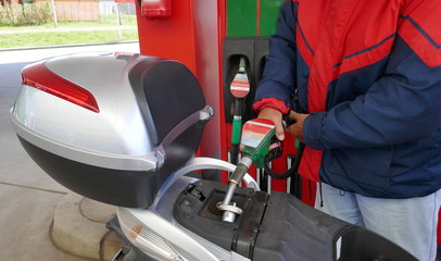 Ein Mann füllt den Tank seines Motorrollers mit Benzin an einer Tankstelle
