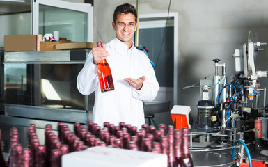 Happy man holding newly produced bottle of wine