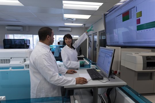 Laboratory technicians discussing over display screen