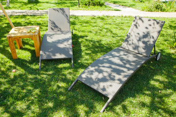two deckchairs on the green grass in the garden on a summer sunny day in the shade.