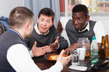 Cheerful men talking at home table