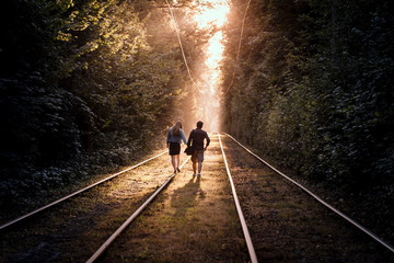 Young happy couple walk along the tram rails at high trees park.