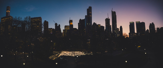 ice rink dawn panorama view from central park to the skyscrapper of new york city with ice skating