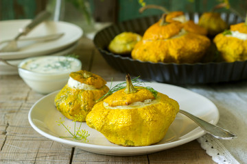 Pattypan squash or pumpkins stuffed with ricotta with basil and dill and served with sour cream sauce. Vegetarian food.