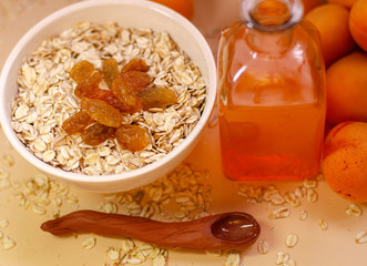 Healthy breakfast. White plate of oatmeal with dried apricots, a glass of an apricot juice and fresh apricots on a white table.