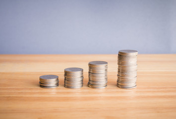 stacks of coin on wooden desk with grey background concept saving money. 