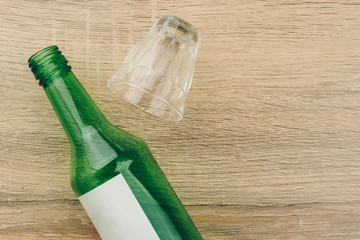 top view of soju bottle with glass on the wooden table. Soju is the colorless distilled beverage,...