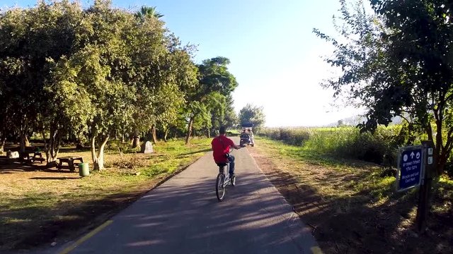 a moving shot of a bike ride through the trees at sunset next to a river and pond in slow motion 60 fps
