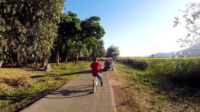 a moving shot of a bike ride through the trees at sunset next to a river and pond in slow motion 60 fps