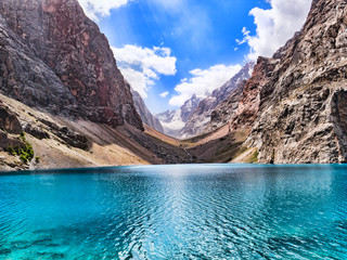 Big Alo mountain lake with turquoise water in sunshine on rocky mountain background. The Fann Mountains, Tajikistan, Central Asia