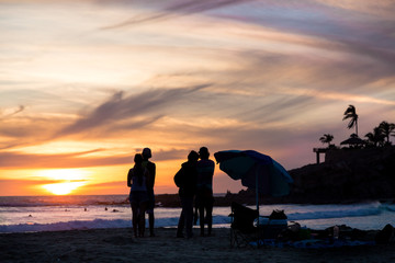 Fototapeta na wymiar Friends standing on a Mexican beach watching a sunset.
