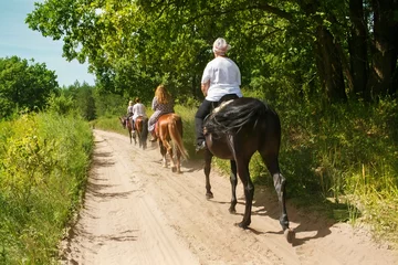 Poster Eine Gruppe von Touristen zu Pferd mit einem Ausbilder für einen Spaziergang. © victoriyasmail
