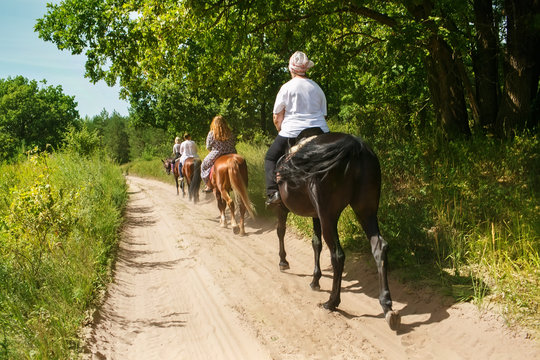 A group of tourists on horseback with an instructor for a walk.