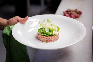 Plate of steak tartar with frisee on top.