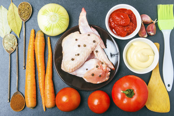 Fresh ingredients for healthy diet with chicken meat. Culinary brush and shovel, spices on silver spoons and tomato paste with mayonnaise on wooden table. Top view
