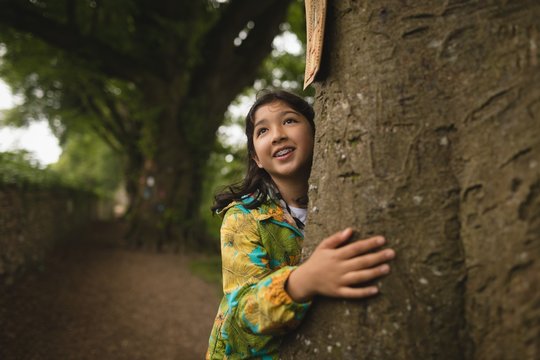 Smiling girl embracing tree outdoors