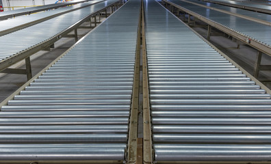 Low, converging perspective of industrial steel roller conveyors.