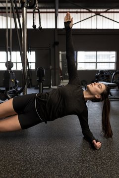 Woman doing side plank exercise in fitness studio