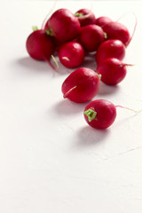 Group of fresh red radishes on white surface, with space for copy