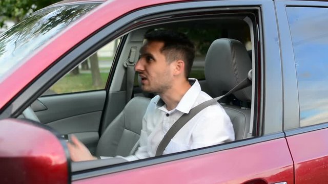 Young driver being impatient, waiting inside his car and showing signs of frustration.