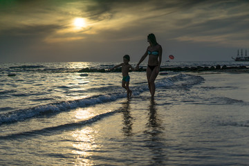 Young mother and smiling baby boy son playing on the beach on the Sunset. Positive human emotions, feelings, joy. Funny cute child making vacations and enjoying summer. Spring and summer holidays.