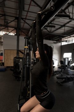 Woman doing pull ups in fitness gym