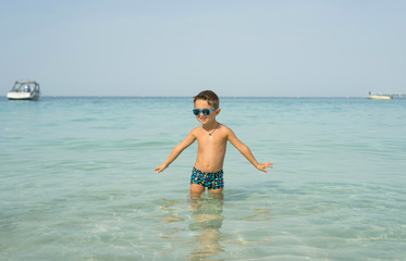 Portrait smiling little baby boy playing in the sea, ocean. Positive human emotions, feelings, joy. Funny cute child making vacations and enjoying summer.