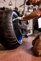 Side view portrait of man working in garage repairing motorcycle