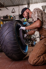 Side view portrait of man working in garage repairing motorcycle