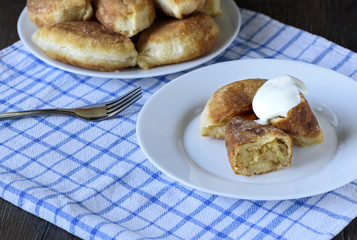 Russian traditional cuisine. Pies with potatoes poured with sour cream.