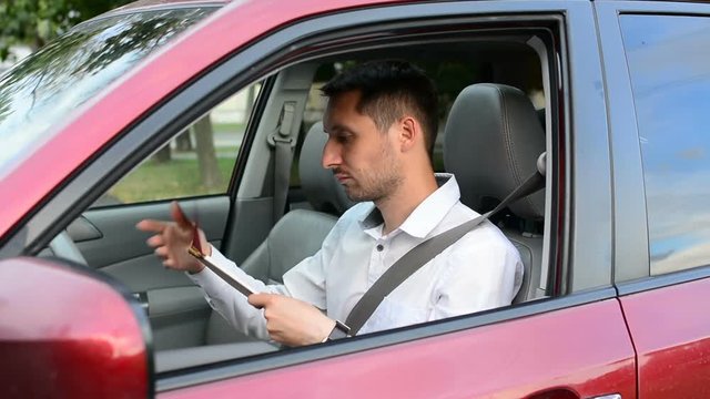 Young driver being impatient, waiting inside his car and showing signs of frustration.