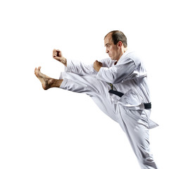 Young athlete strikes with a kick forward on a white background isolated