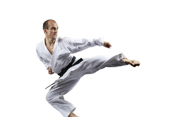 A man with a black belt trains a kick in a jump isolated