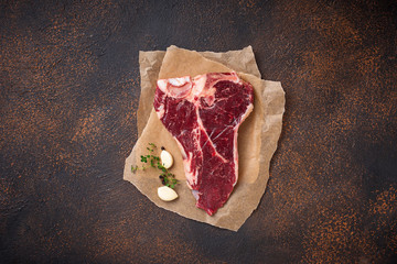Raw T-bone steak with garlic and thyme 