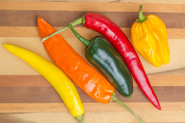 red, green, yellow and orange chillies on isolated wood background
