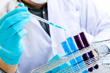 Biochemistry laboratory research, Scientist or medical in lab coat holding test tube with reagent with drop of color liquid over glass equipment working at the laboratory