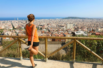 Excited attractive young woman in sportswear stretching enjoying Barcelona cityscape in the morning. Cheerful mood, true emotions, healthy lifestyle.