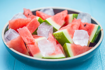 slices of watermelon in a plate with ice on a blue background