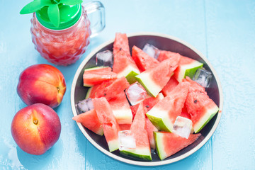 slices of watermelon in a plate with ice and peaches on a blue background