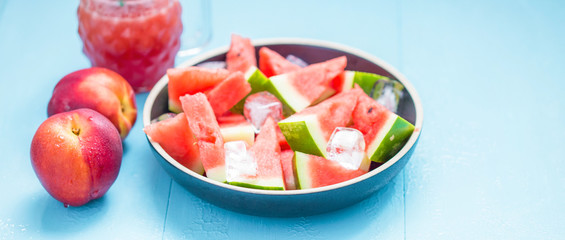 slices of watermelon in a plate with ice and peaches on a blue background