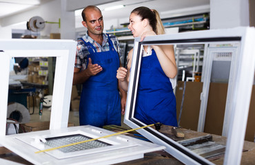 Foreman explaining plastic windows assembly process to young female worker