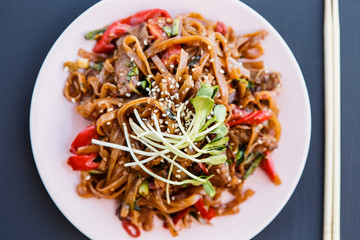 A plate ofwok beef noodles on the dark background