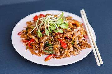 A plate ofwok beef noodles on the dark background
