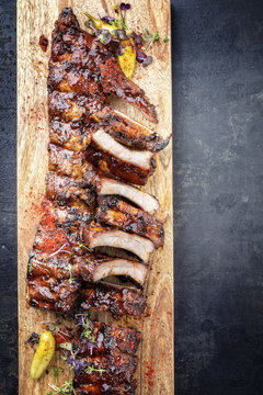 Barbecue spare ribs St Louis cut with hot honey chili marinade and chili as top view in a wooden cutting board with copy space right