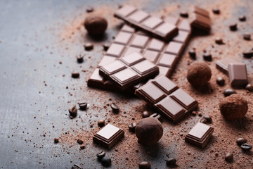 Chocolate pieces with coffee beans and cocoa powder on wooden table