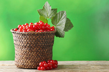 Red currants in wicker basket on grey wooden table