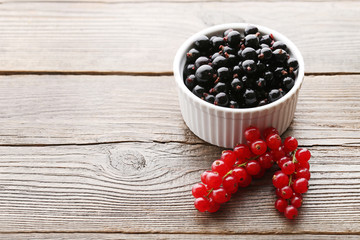 Black currants in bowl on grey wooden table