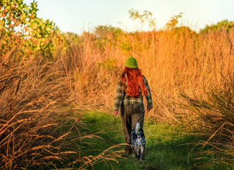 Woman with a dog walking  towards  the dry prairie grasses in the fall in Missouri