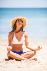 Fototapeta na wymiar Beautiful latin girl in yoga position on the beach during tropical vacation